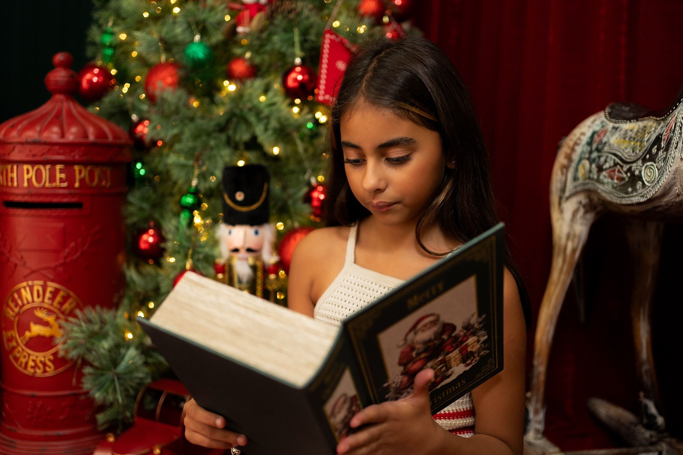 Menina lendo um livro de Natal no cenário