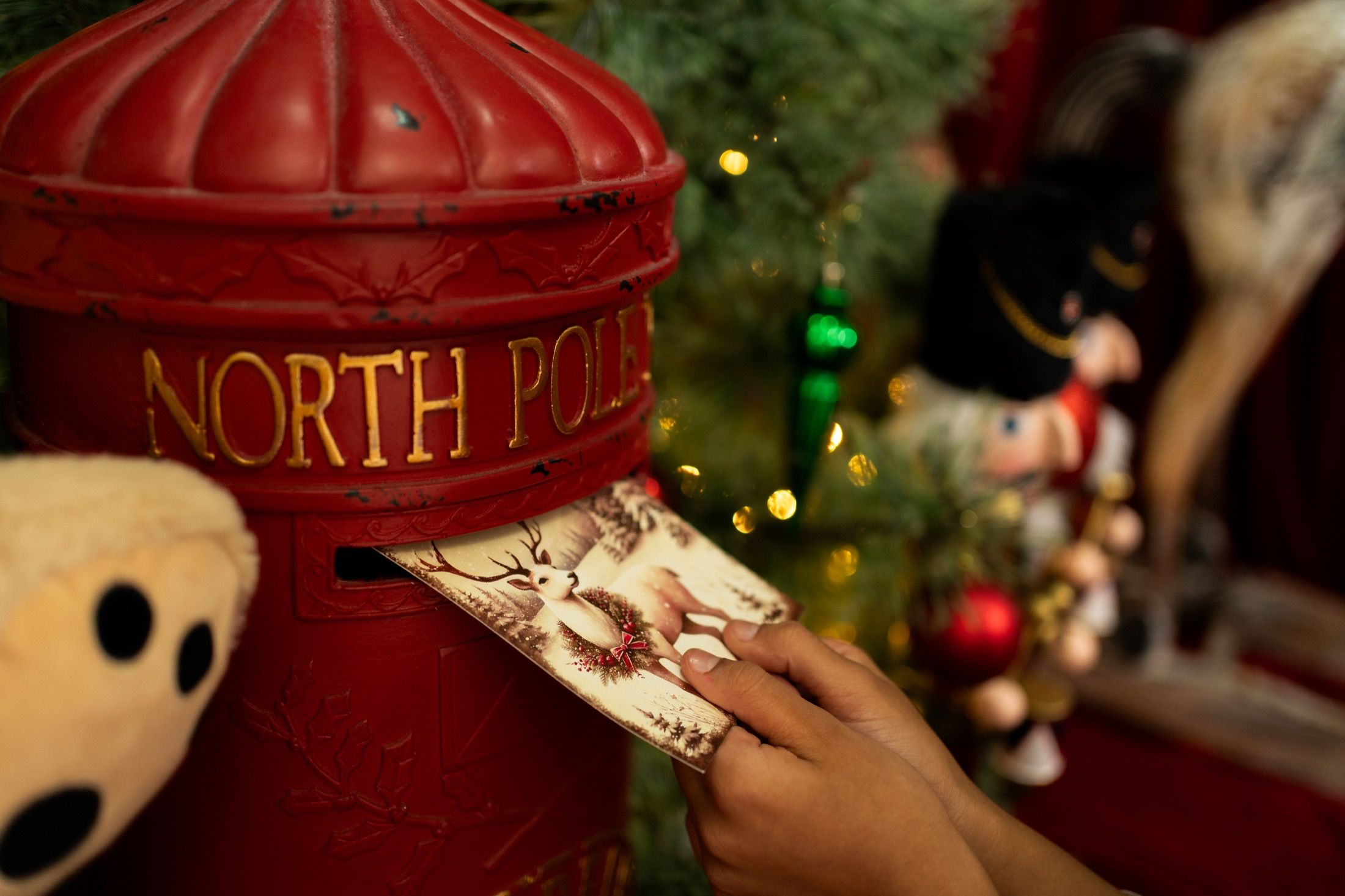 Mãos colocando uma carta na caixa de correio North Pole